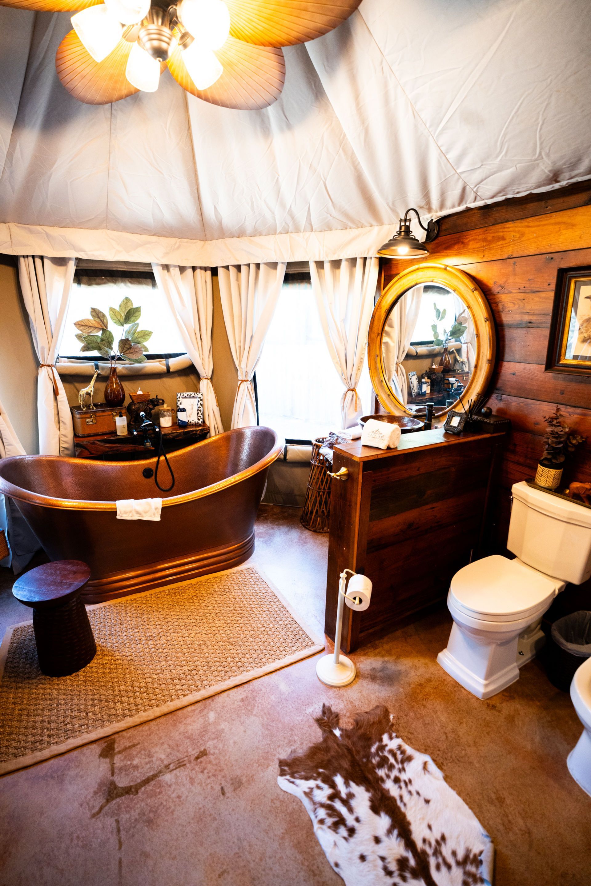 Luxurious bathroom with copper tub, wooden vanity, and a cowhide rug.