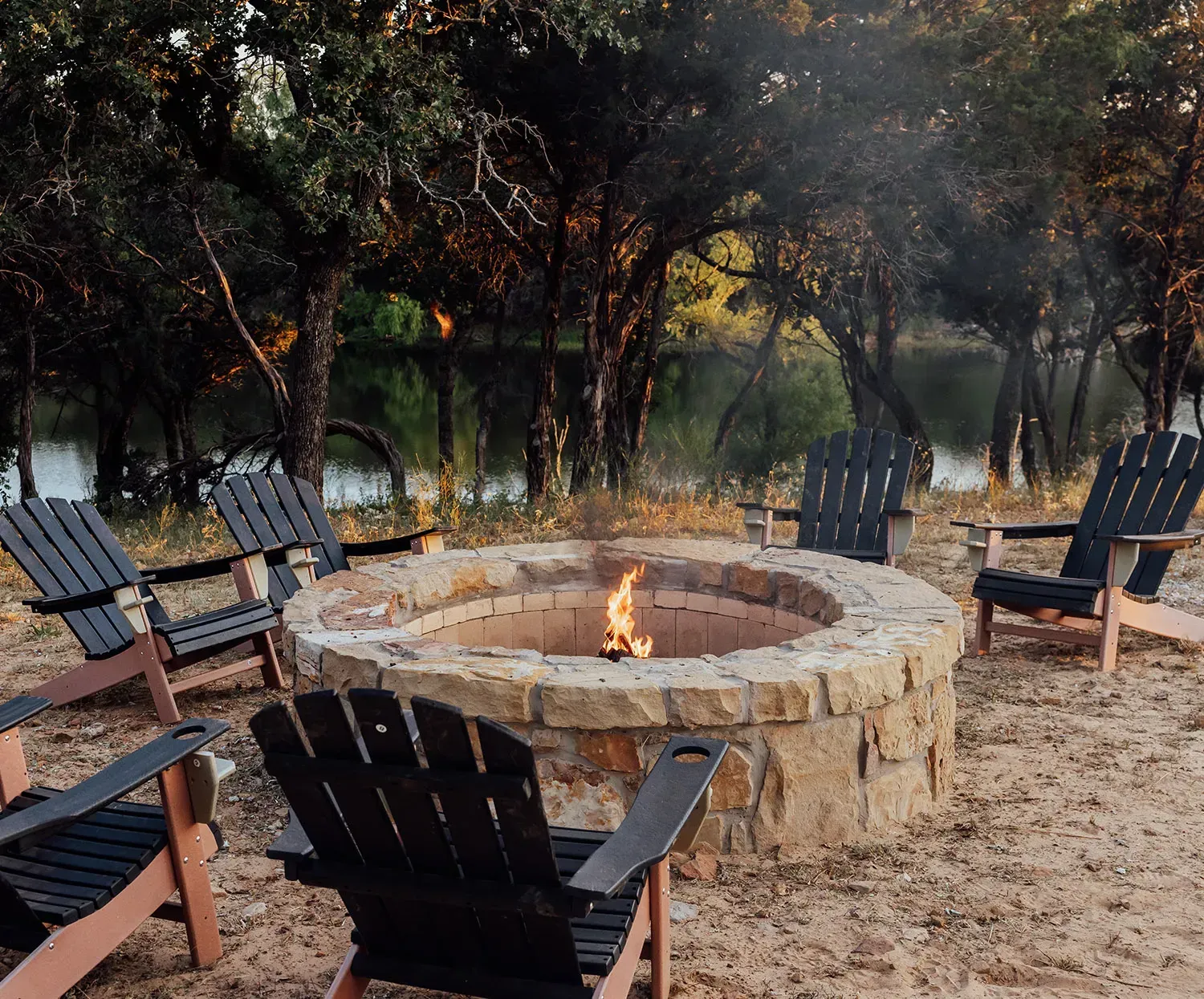 Man grilling food outdoors at sunset.