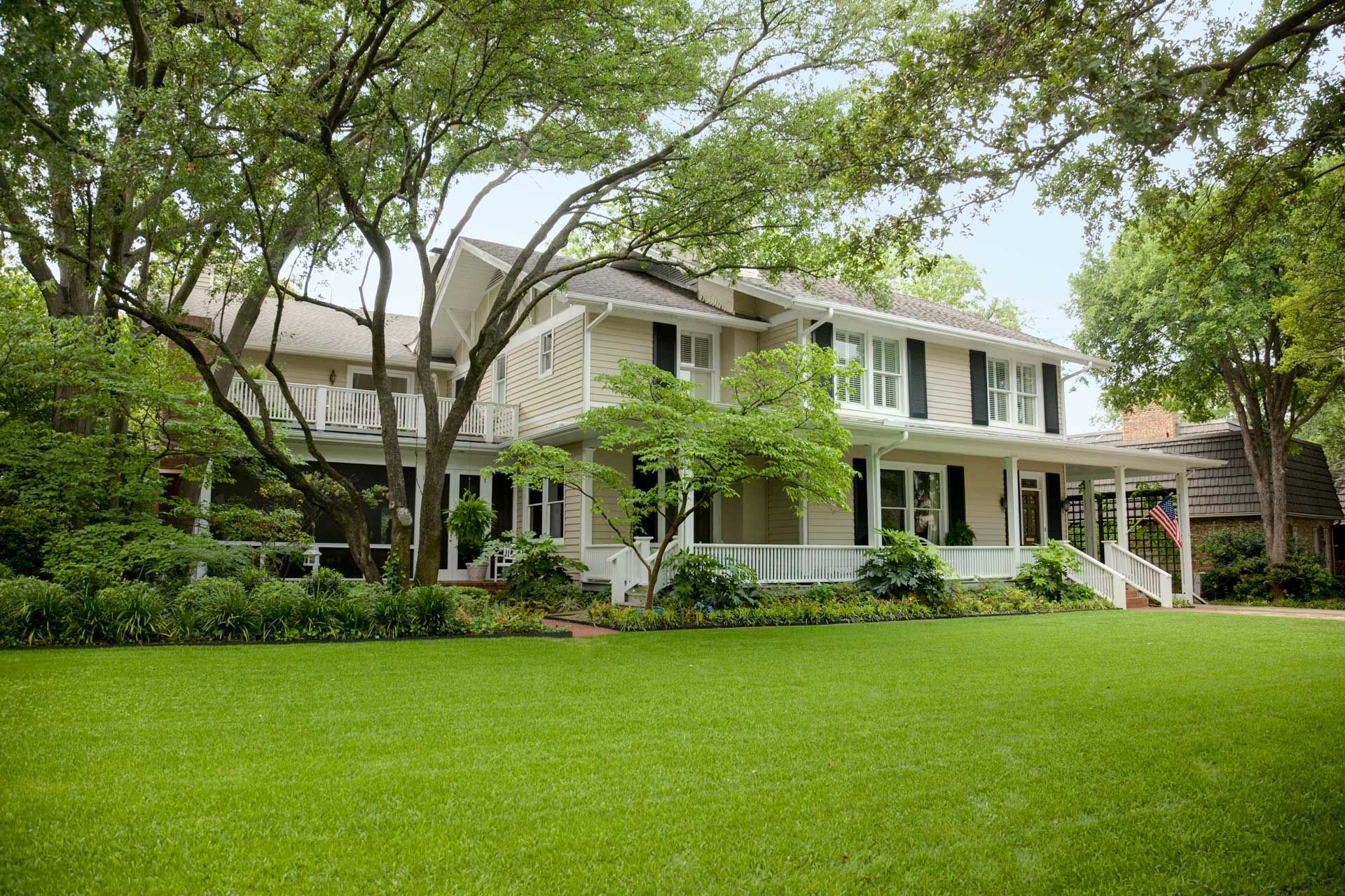 Large white house with green lawn and trees.