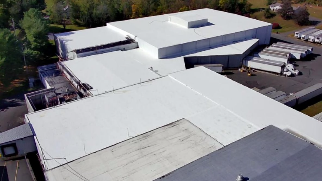 An aerial view of a large building with a white roof.