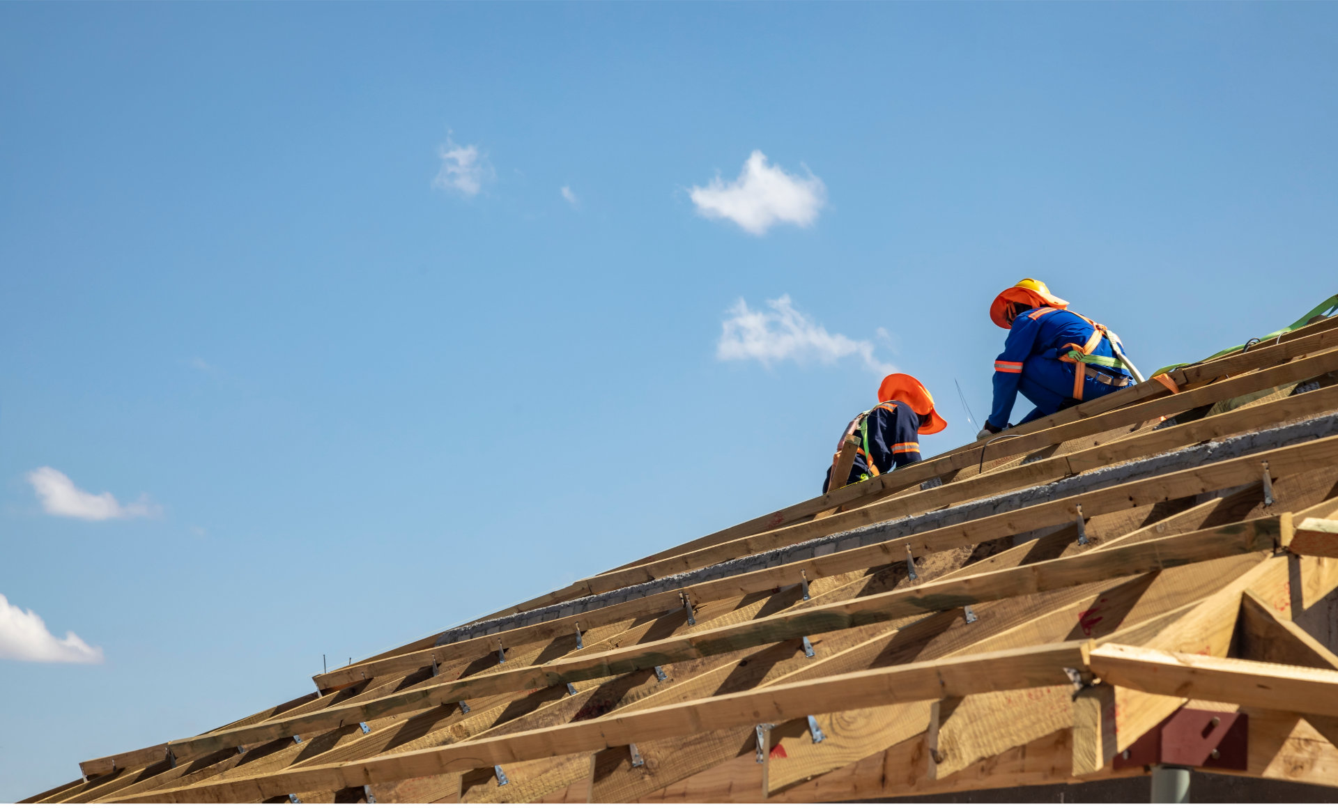 Two construction workers are working on a wooden roof.