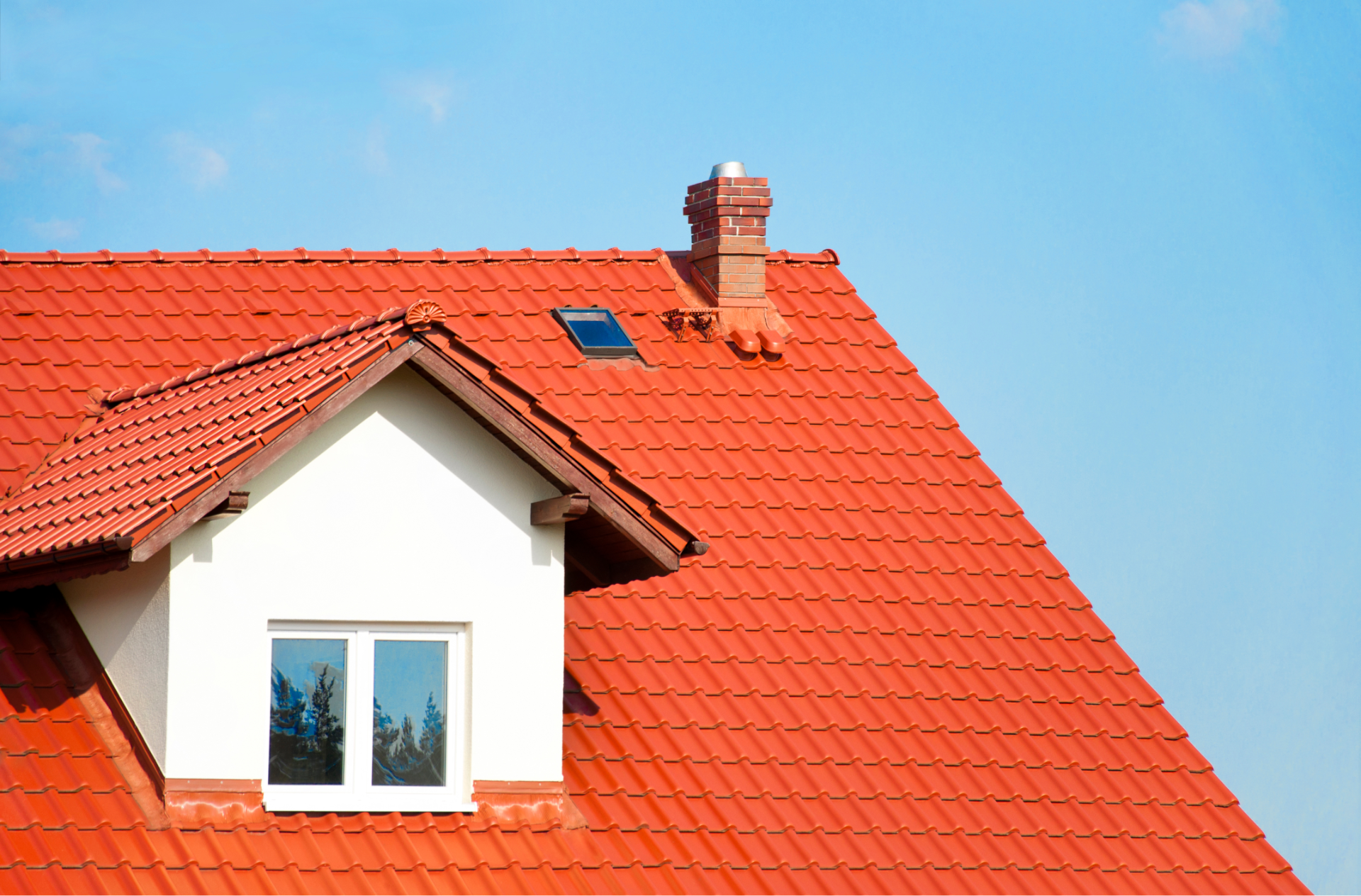 The roof of a house with a red tile roof and a window.