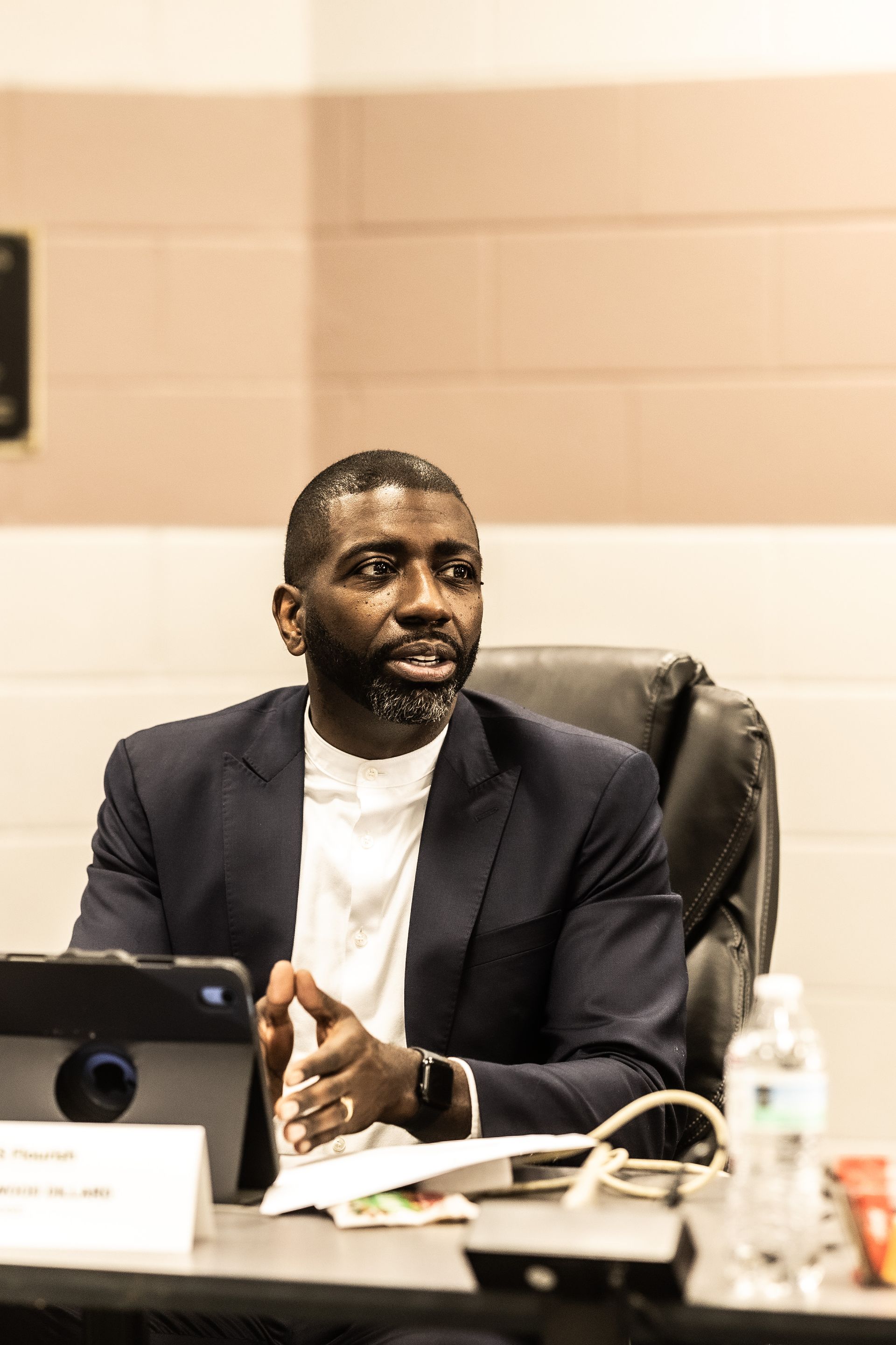 A man in a suit is sitting at a table with a tablet.