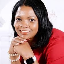 A woman wearing a red shirt and a smart watch is smiling.