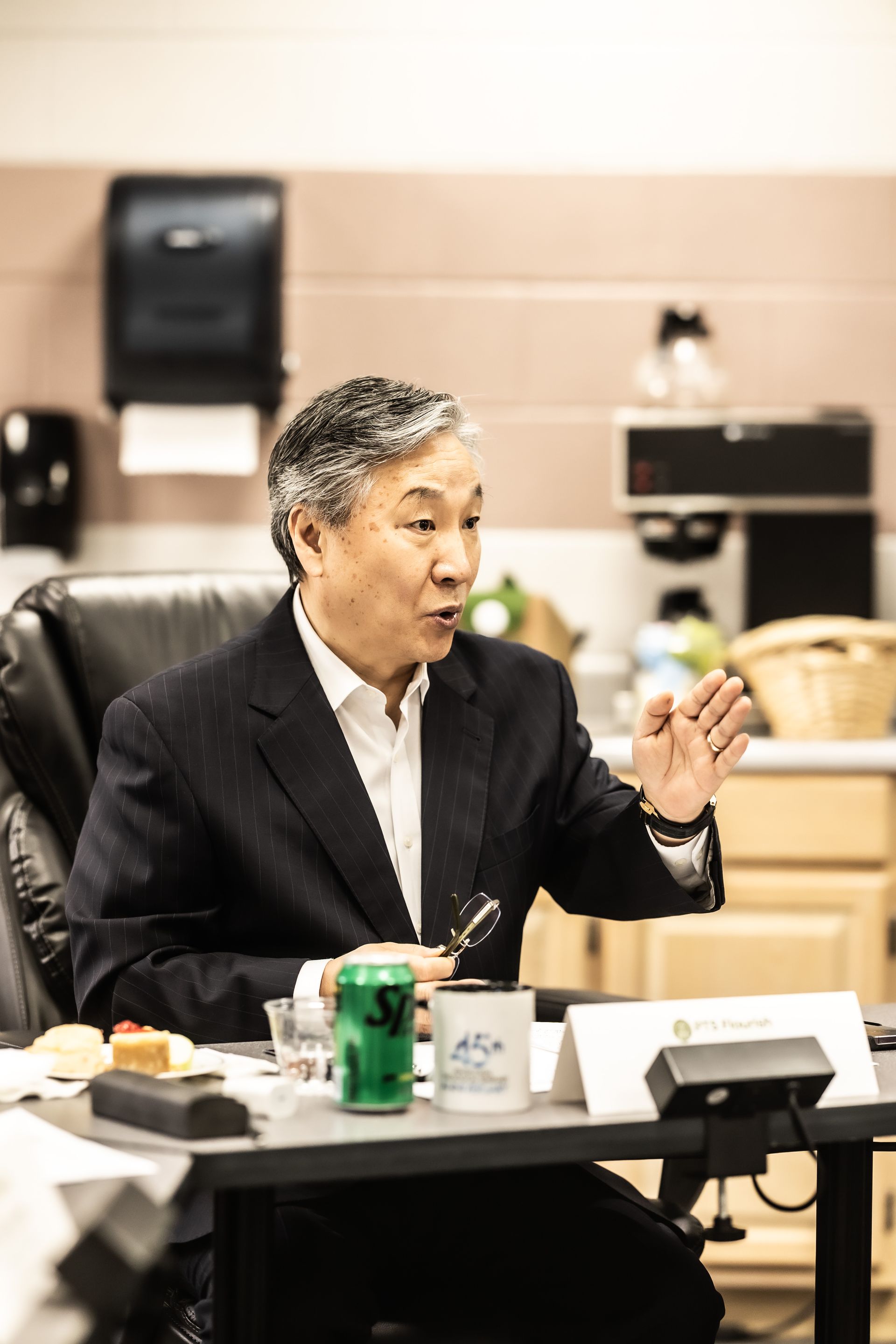 A man in a suit is sitting at a table with a can of sprite on it.