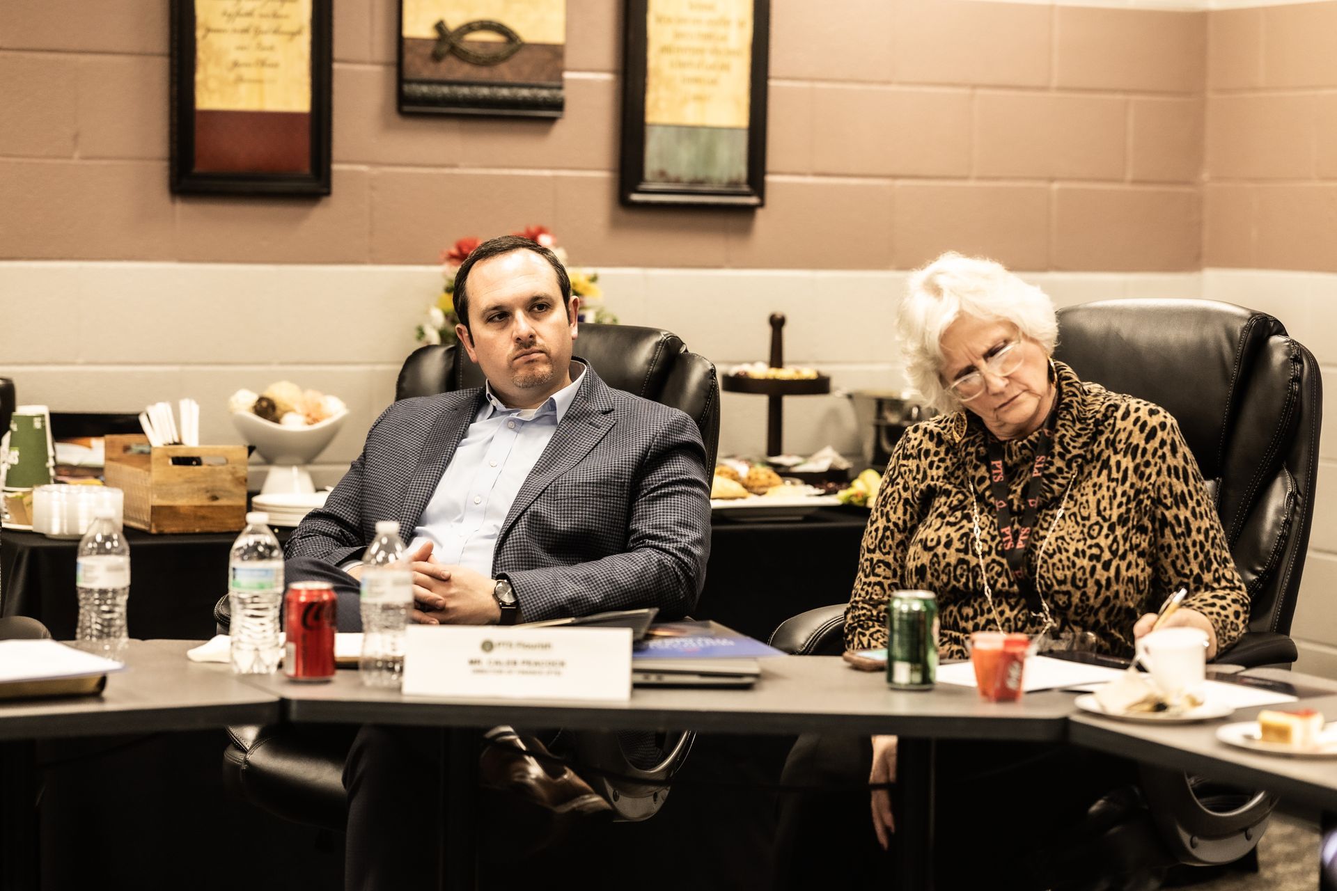 A man and a woman are sitting at a table in a conference room.