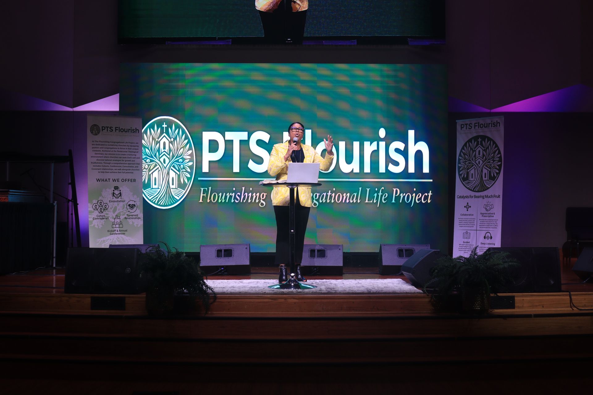 A man is standing in front of a large screen that says ptsurish