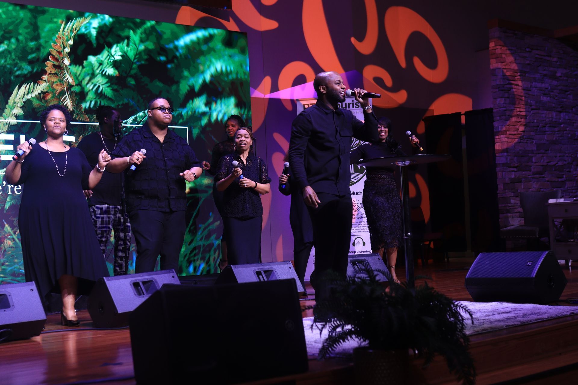 A group of people singing into microphones on a stage