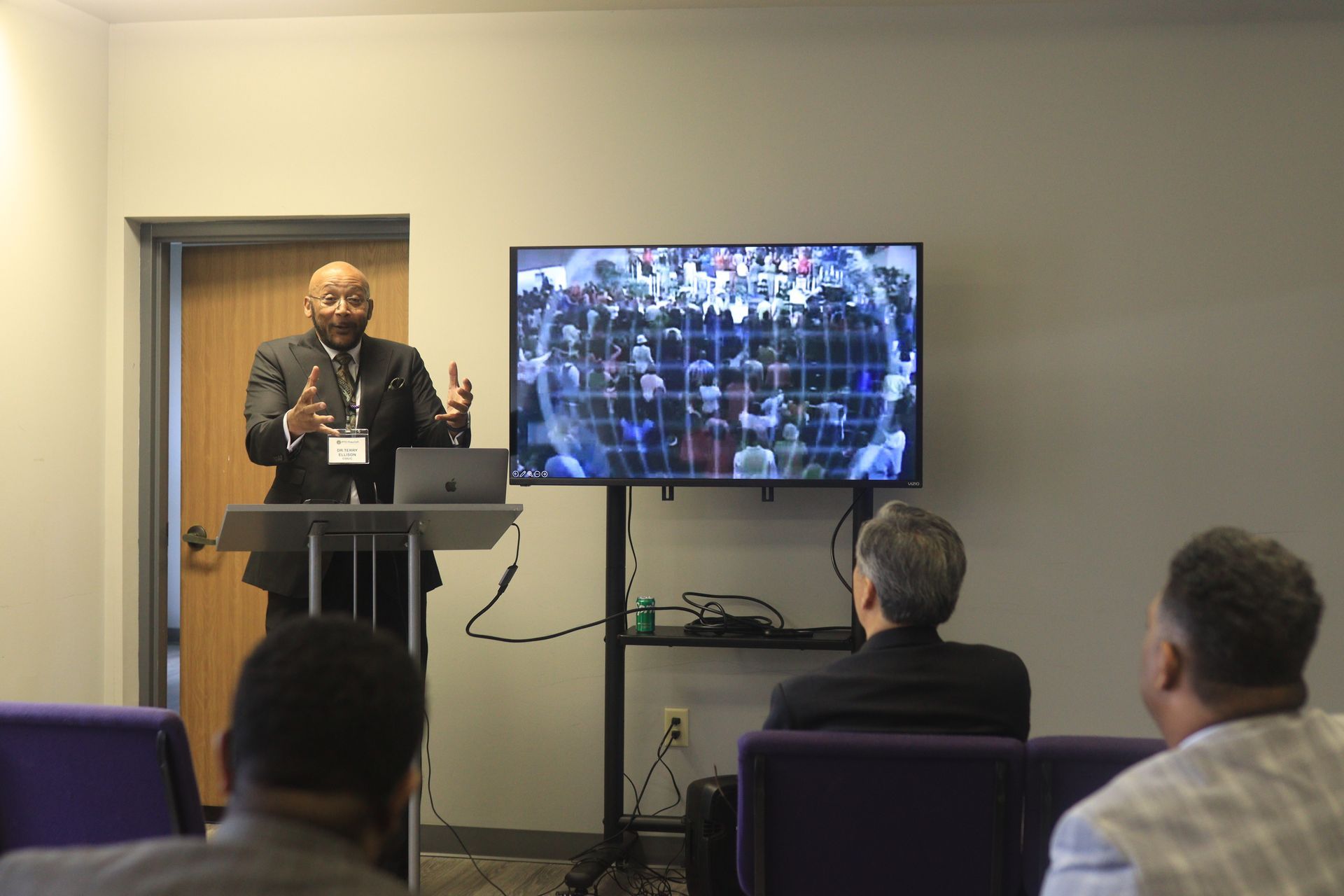 A man is standing at a podium giving a presentation to a group of people.