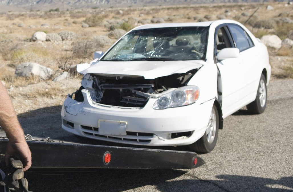 Damaged white car on a road, front-end collision, tow truck present — Downs Towing & Recovery Service in Dalby, QLD