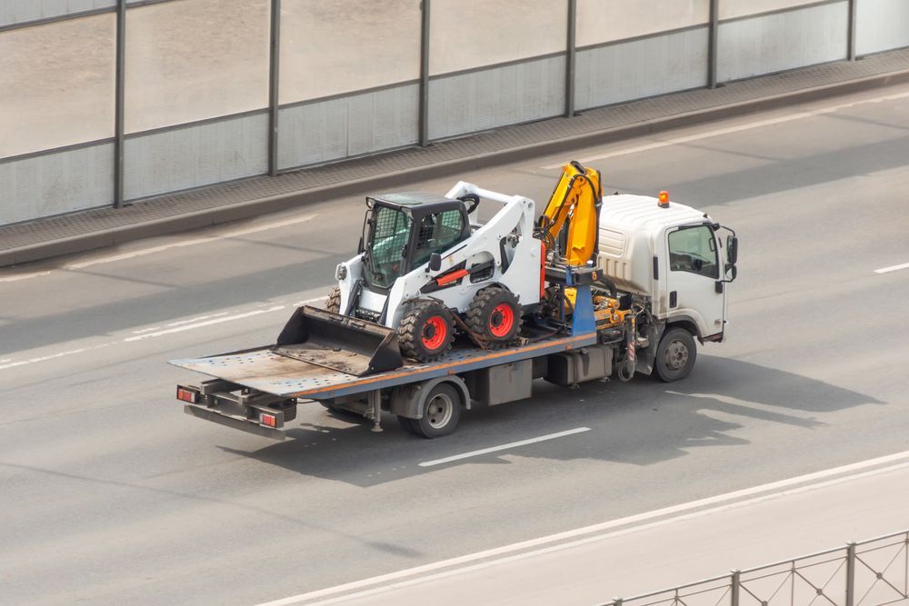 White Truck Hauling a White and Orange Bobcat Construction Vehicle — Downs Towing & Recovery Service in Chinchilla, QLD