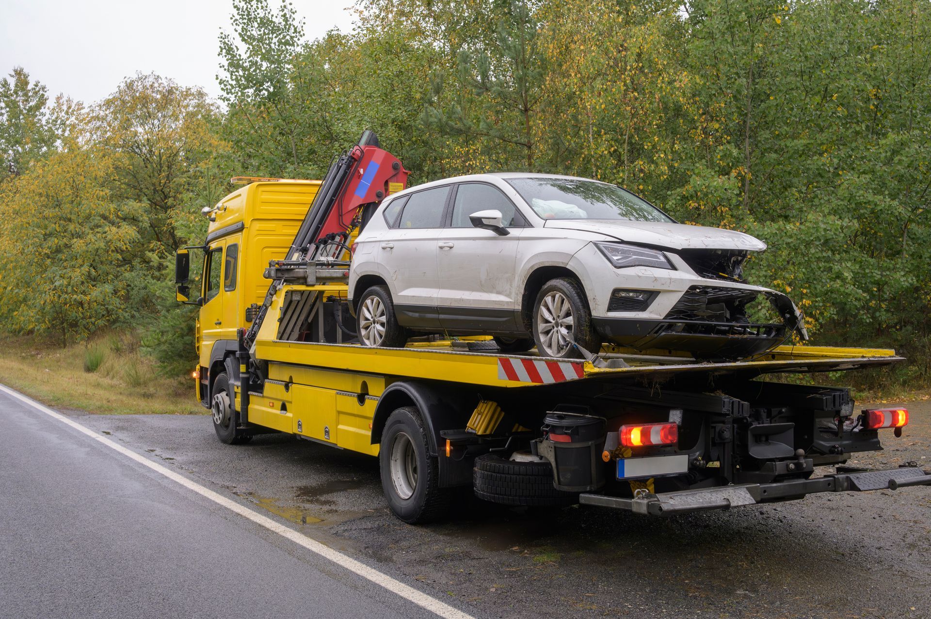 Yellow Tow Truck With Damaged White Car on Its Flatbed, Roadside Setting — Downs Towing & Recovery Service in Chinchilla, QLD