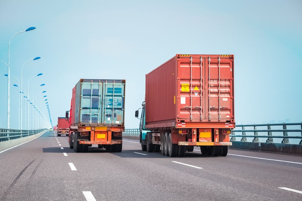 Trucks Carrying Shipping Containers on a Bridge With a Blue Sky Background — Downs Towing & Recovery Service in Dalby, QLD