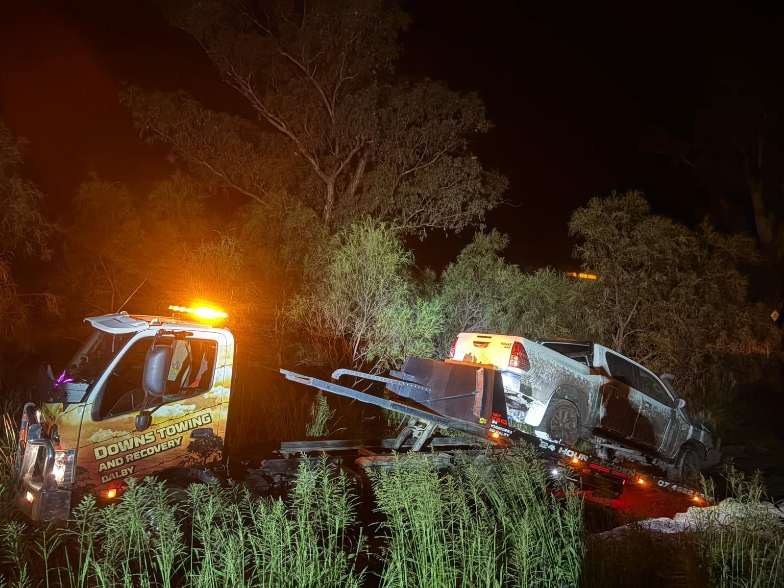 Tow Trucks Recover A Wrecked Car At Night, With Flashing Orange Lights In A Dark Roadside Ditch — Downs Towing & Recovery Service in Dalby, QLD