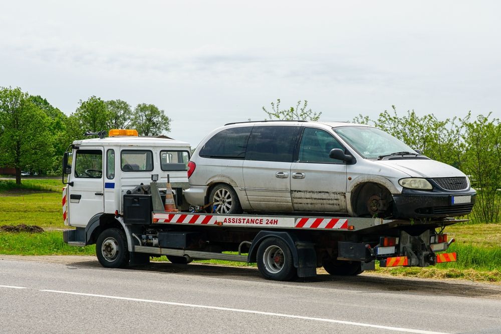 Tow Truck Carrying a Damaged White Minivan on a Roadside — Downs Towing & Recovery Service in Chinchilla, QLD