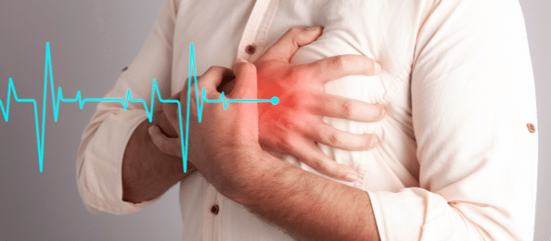A man is holding his chest in pain because of a heart attack.