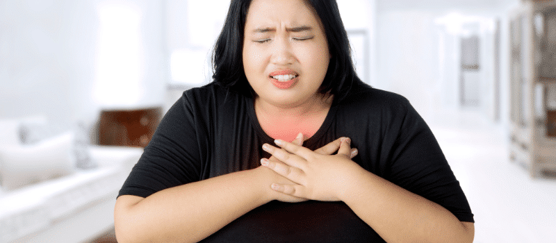 A woman is holding her chest in pain.