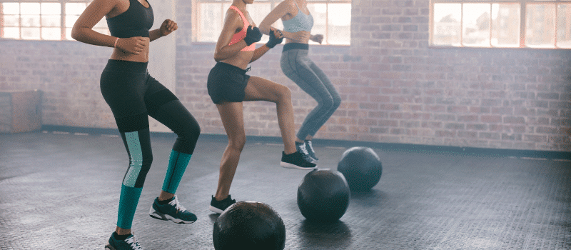 Three women are doing exercises with medicine balls in a gym.
