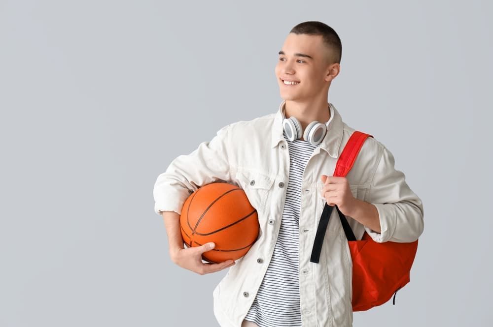 A young man with a backpack is holding a basketball.
