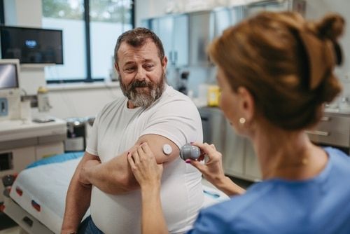 A man is getting an injection from a nurse in a hospital room.