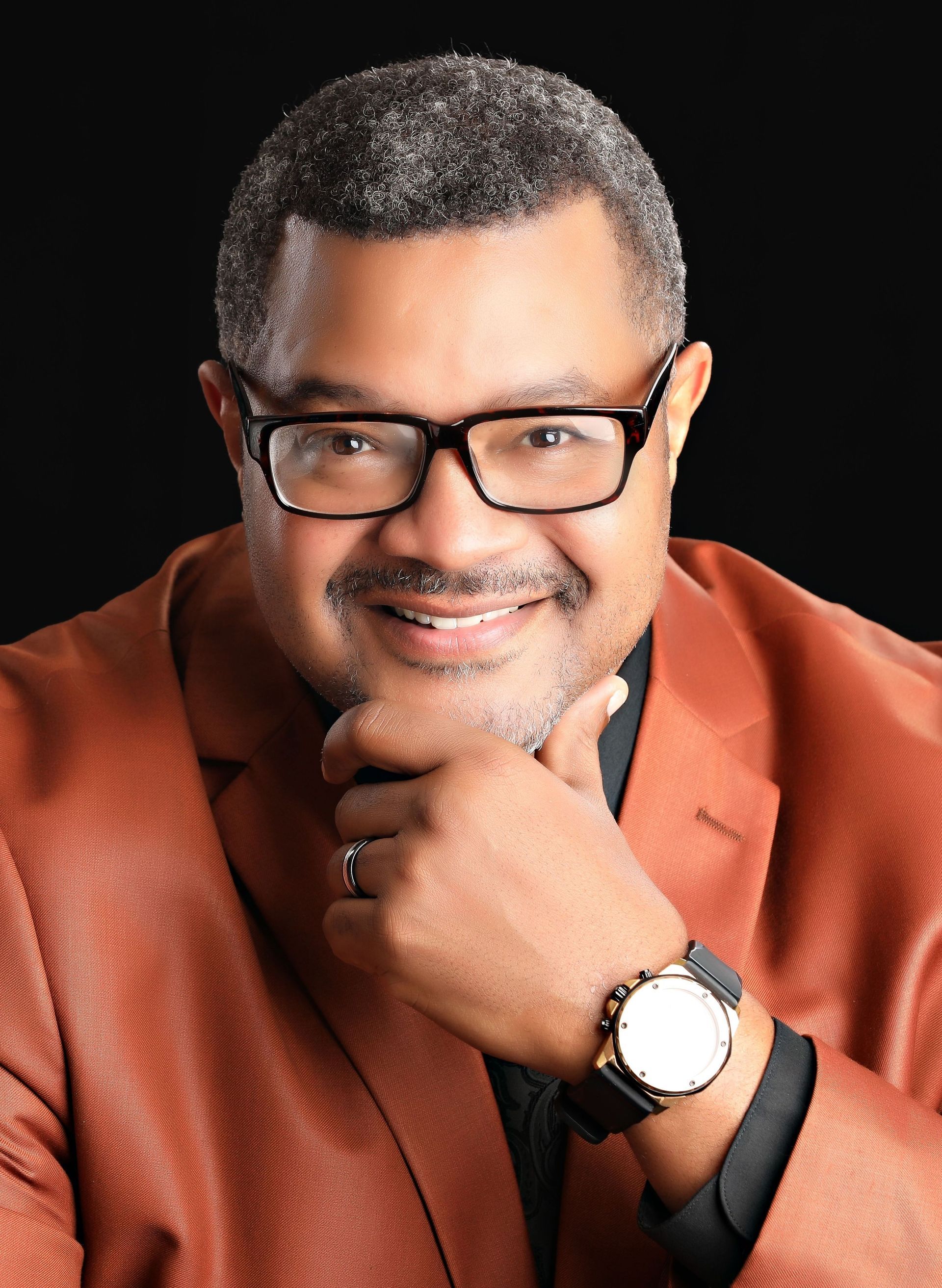 A woman is sitting at a desk with a laptop and a vase of flowers.