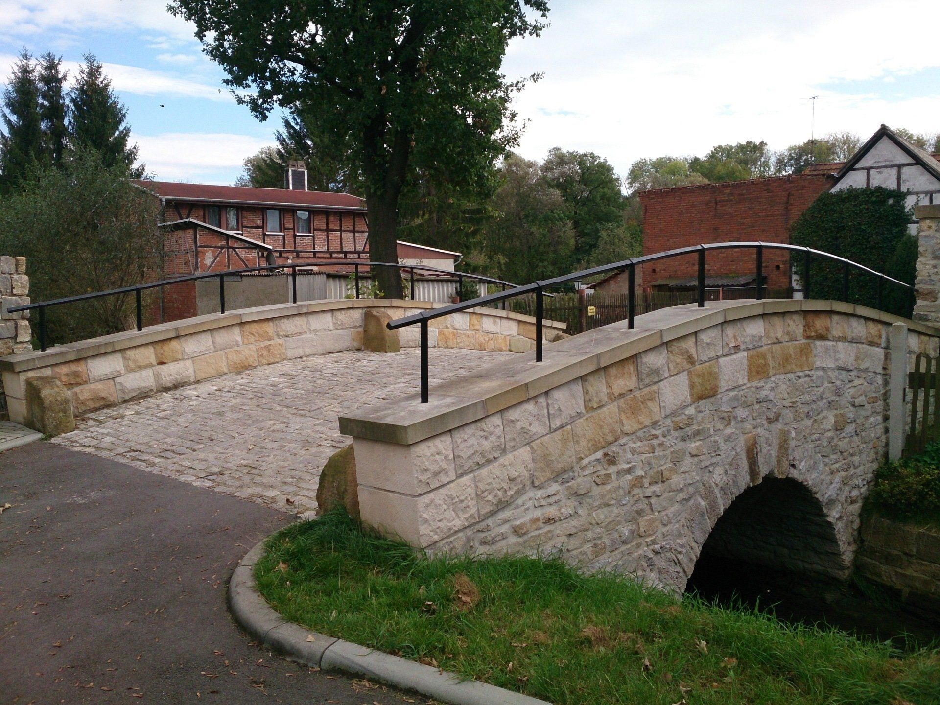 Eine Steinbrücke mit einem schwarzen Geländer über einem Fluss