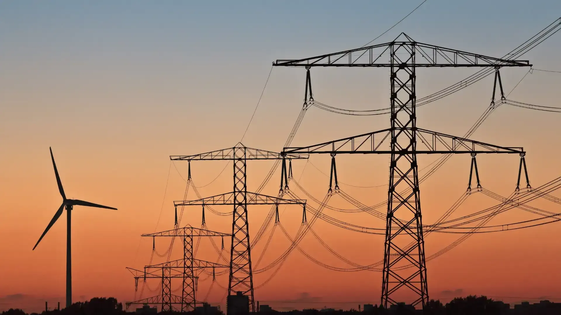 a row of power lines with a wind turbine in the background