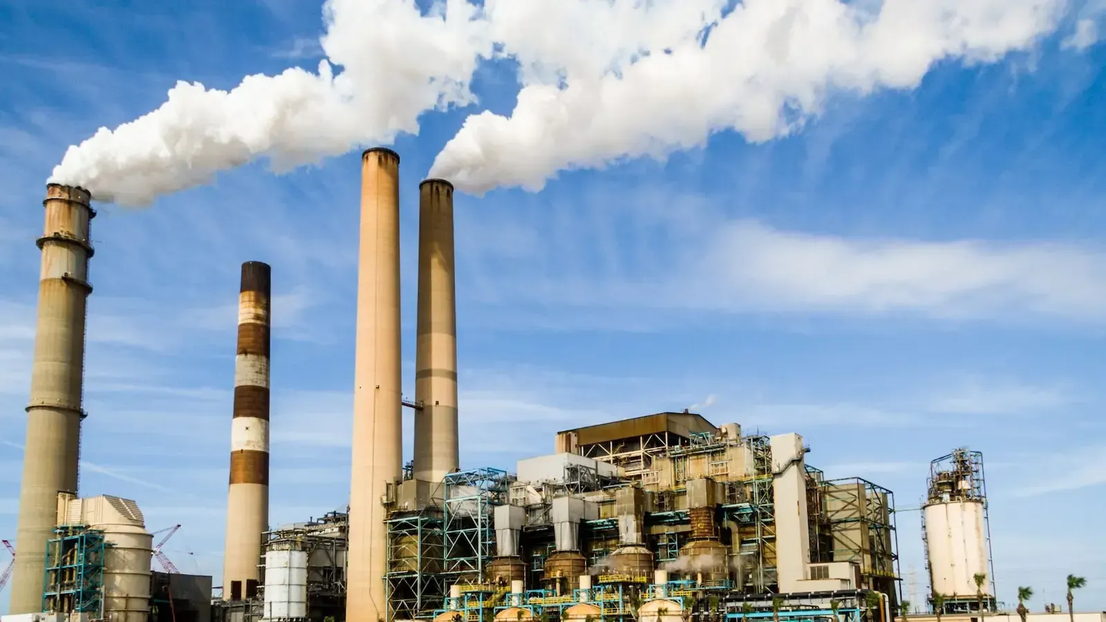 A factory with smoke coming out of the chimneys.
