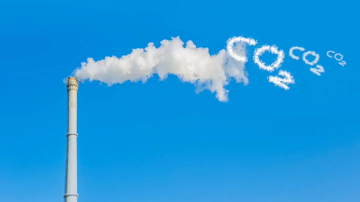 Smoke is coming out of a chimney against a blue sky.