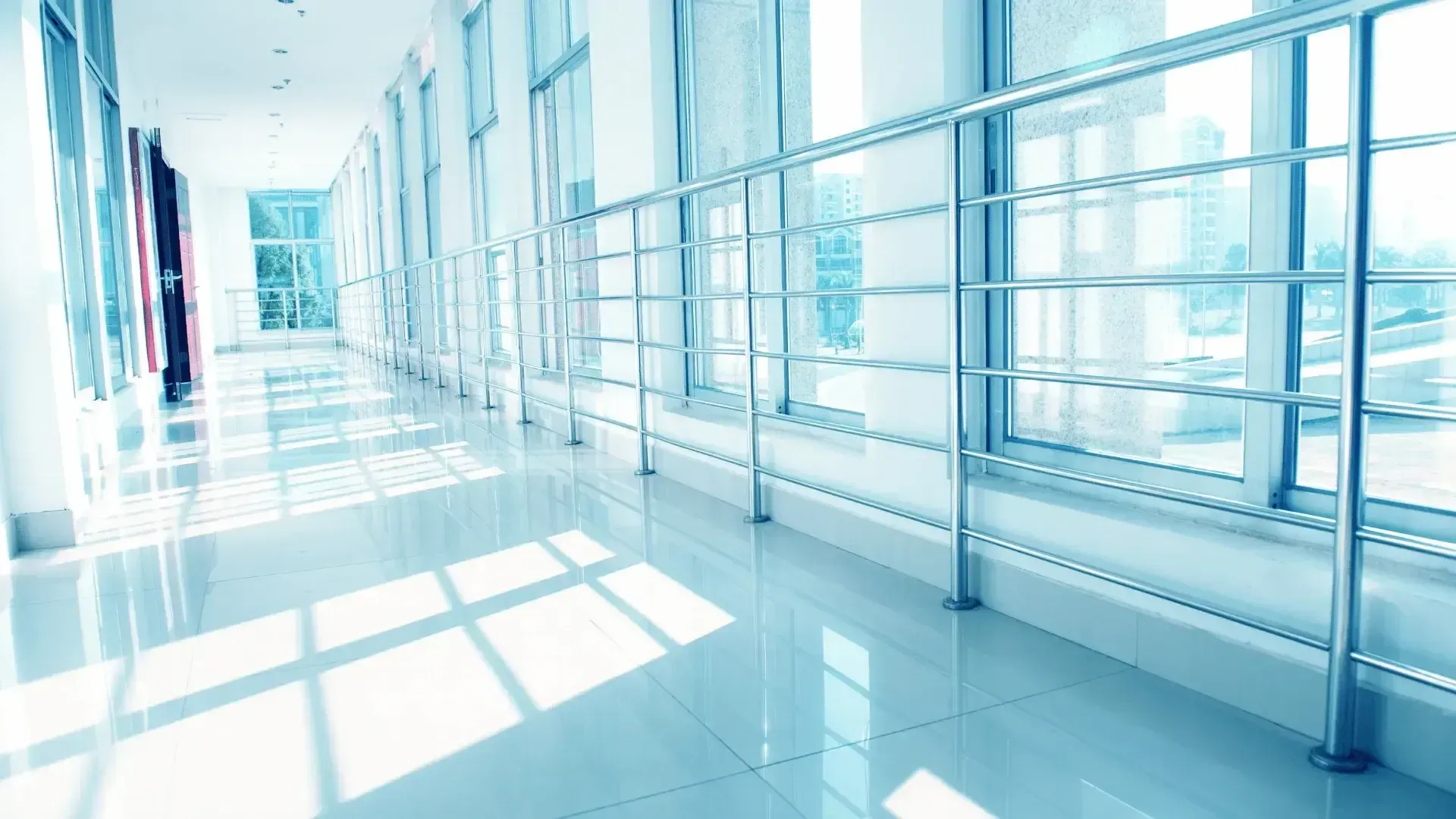 A long hallway with lots of windows and a metal railing.