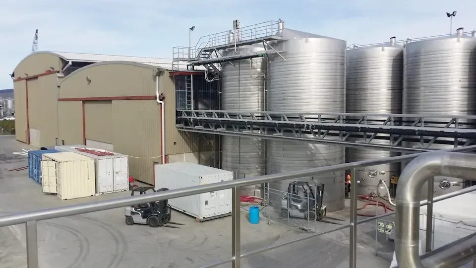 A row of stainless steel tanks are sitting in front of a building.