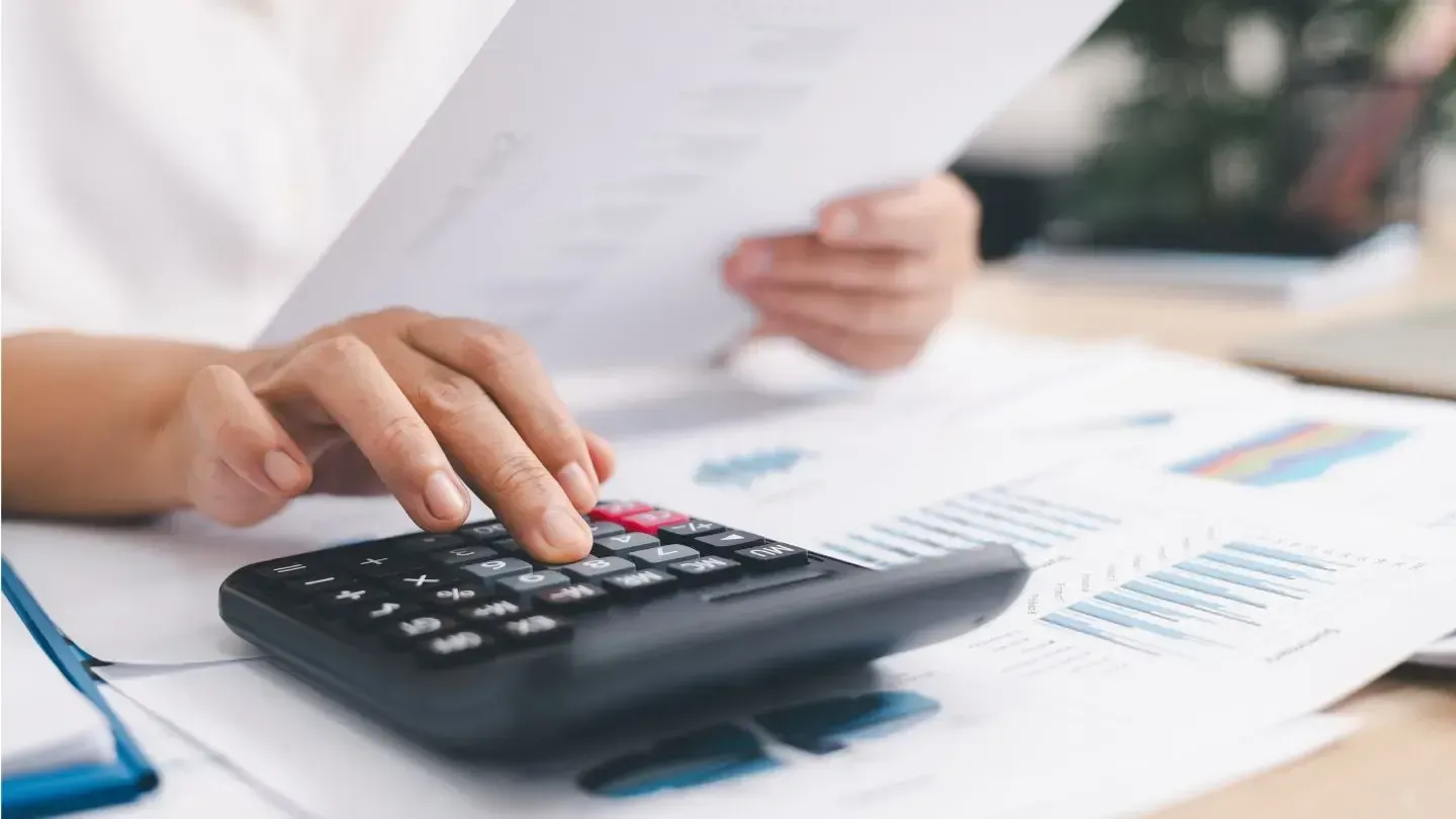 Person using calculator with papers, possibly for financial calculations.