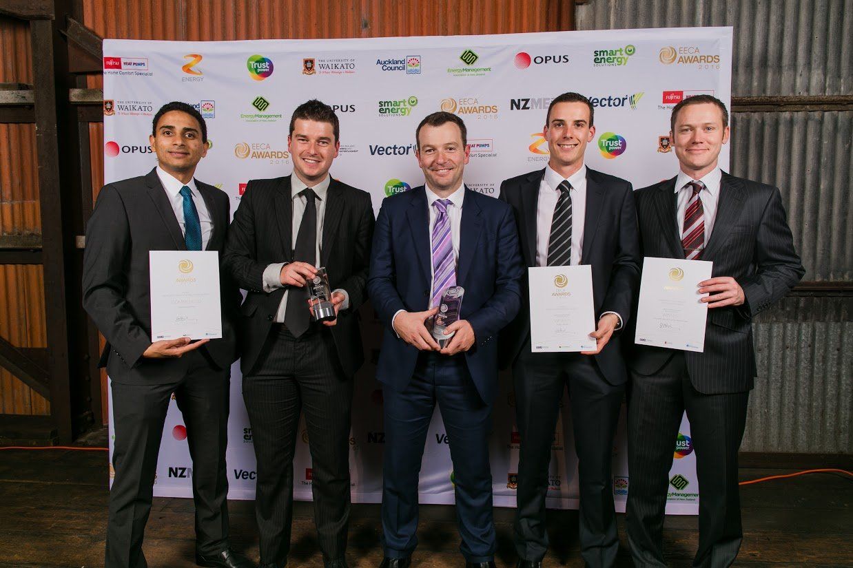 a group of men in suits and ties are standing next to each other holding trophies .