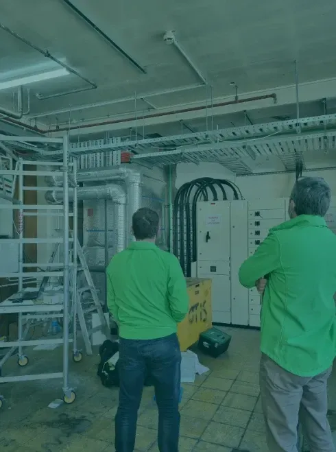 Two men in green shirts are standing in a room
