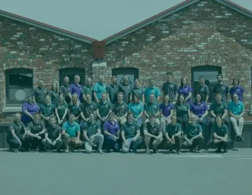 A large group of people are posing for a picture in front of a brick building.