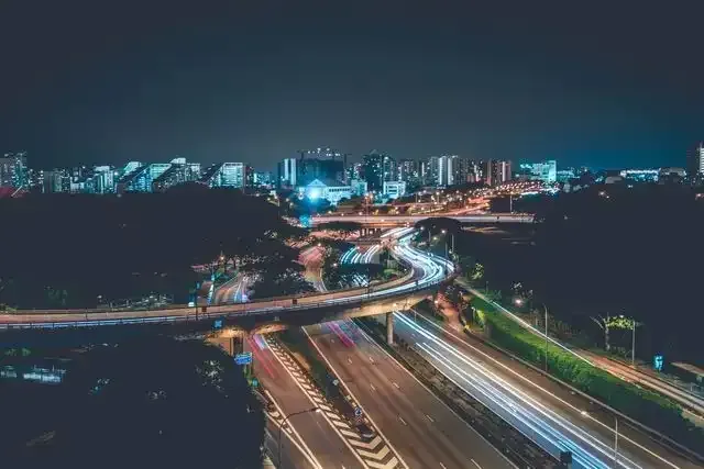 an aerial view of a highway at night with a city in the background .