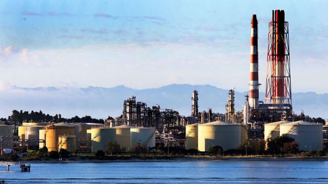 a large oil refinery is sitting next to a body of water .