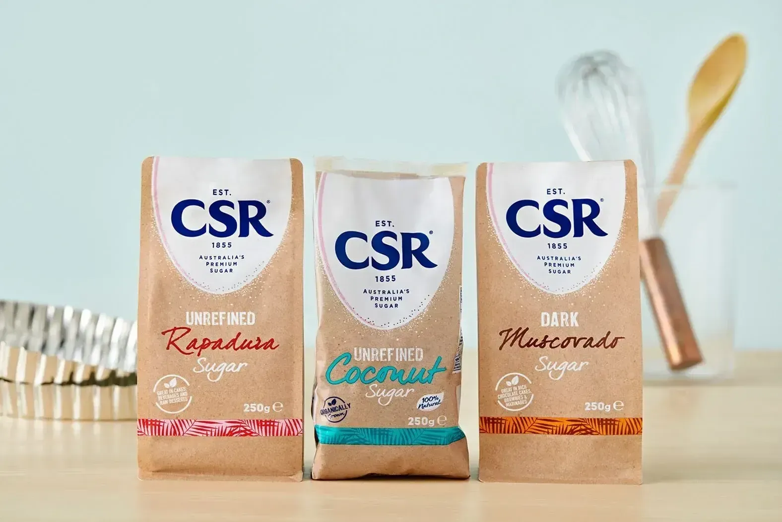 Three bags of csr sugar are sitting on a wooden table.