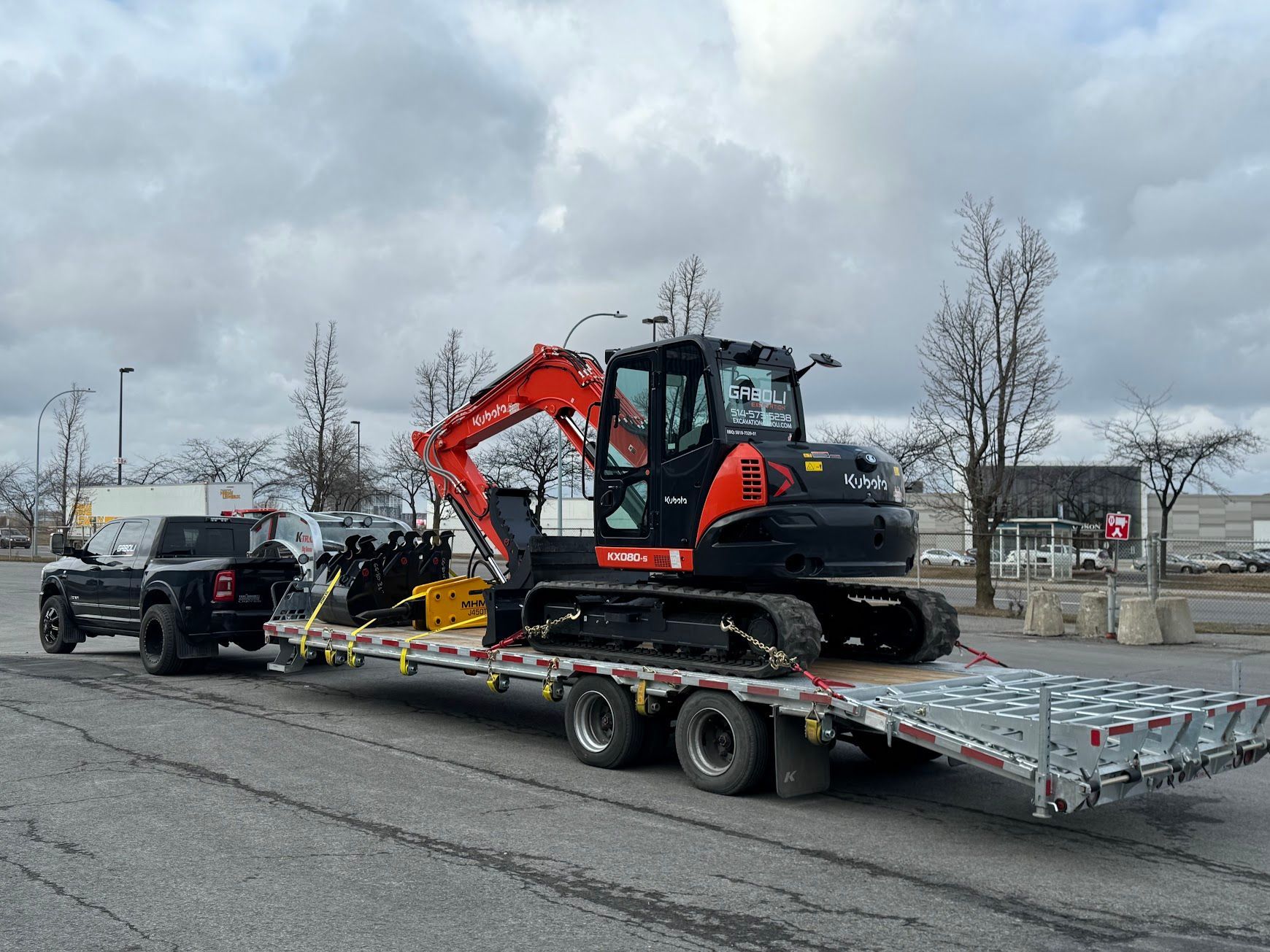 Un camion tire une remorque avec une excavatrice dessus.