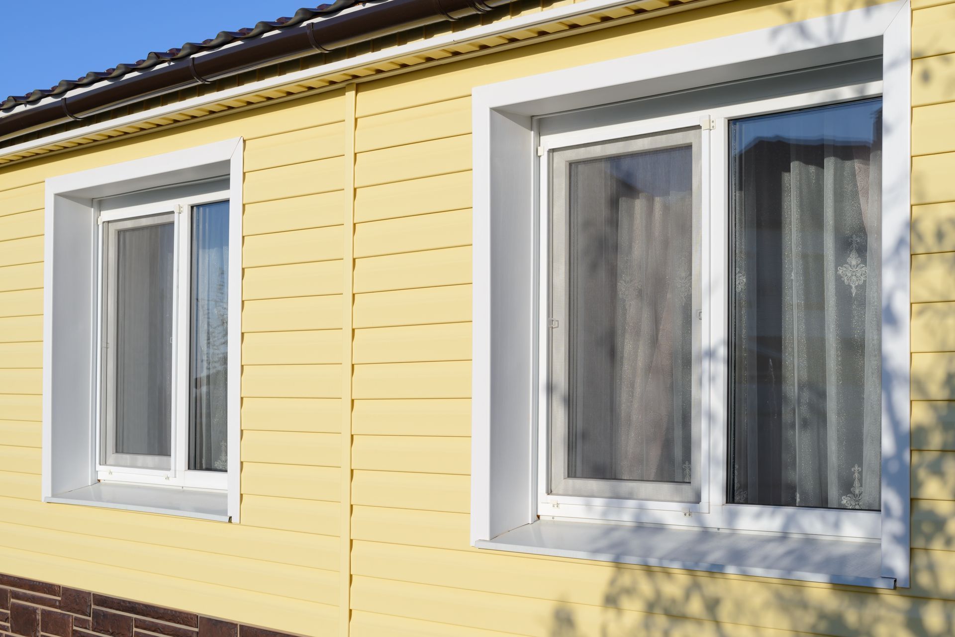 A yellow house with two windows on the side of it.