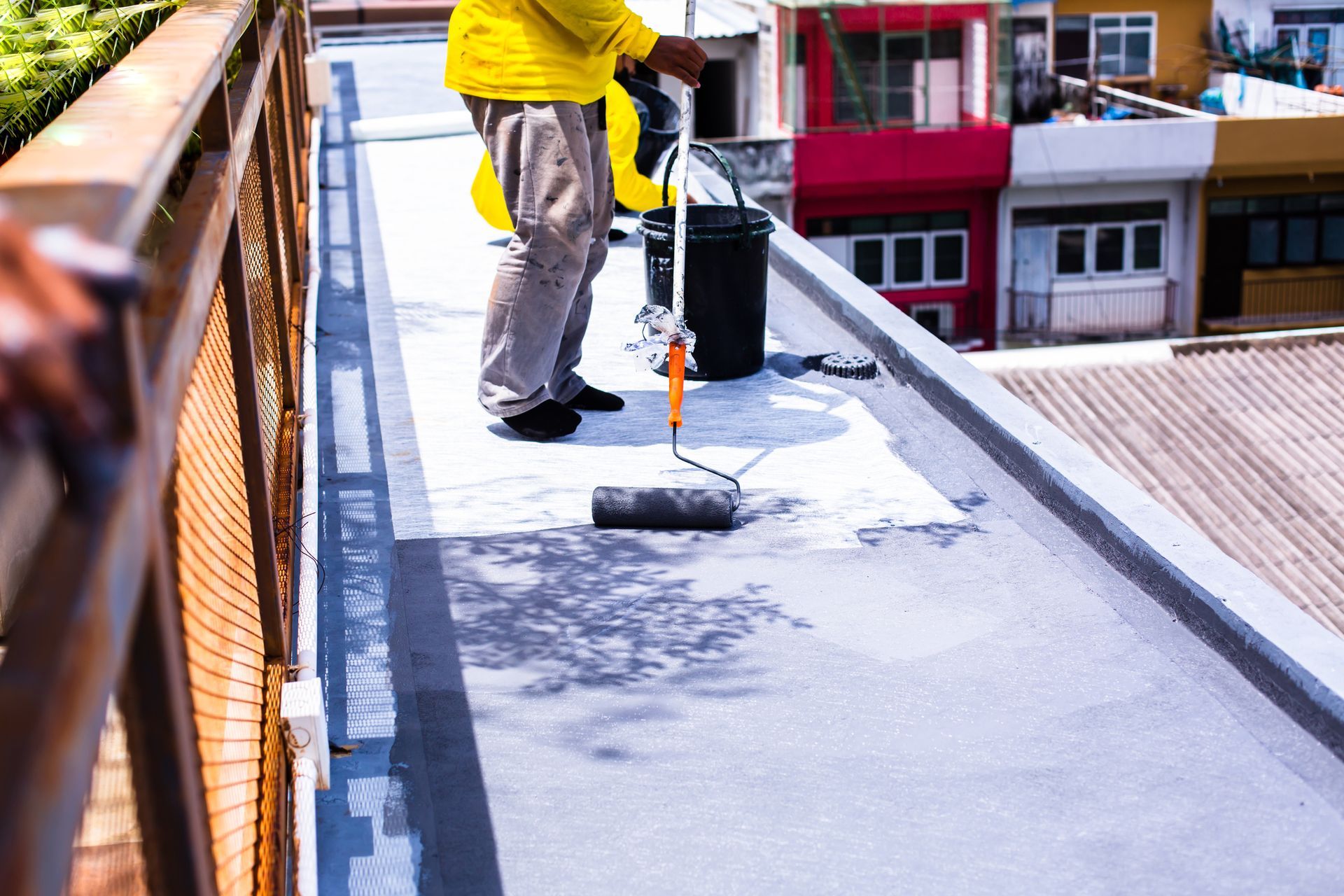 A man is painting a roof with a roller.