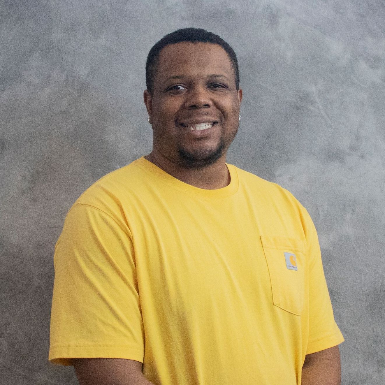 A man in a yellow shirt is smiling for the camera