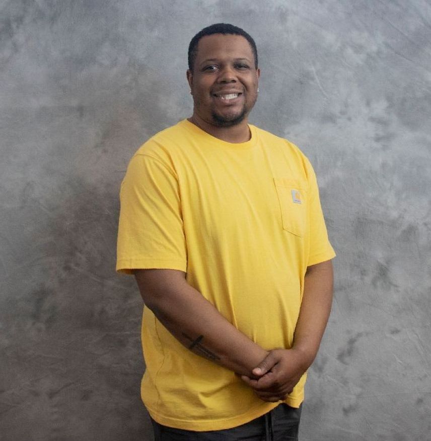 A man in a yellow shirt is smiling for the camera