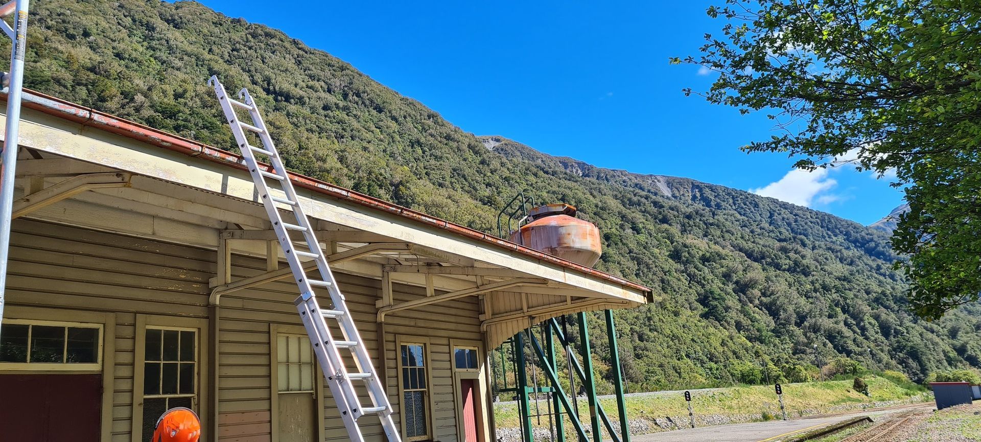 A man is standing on a ladder on the roof of a building.