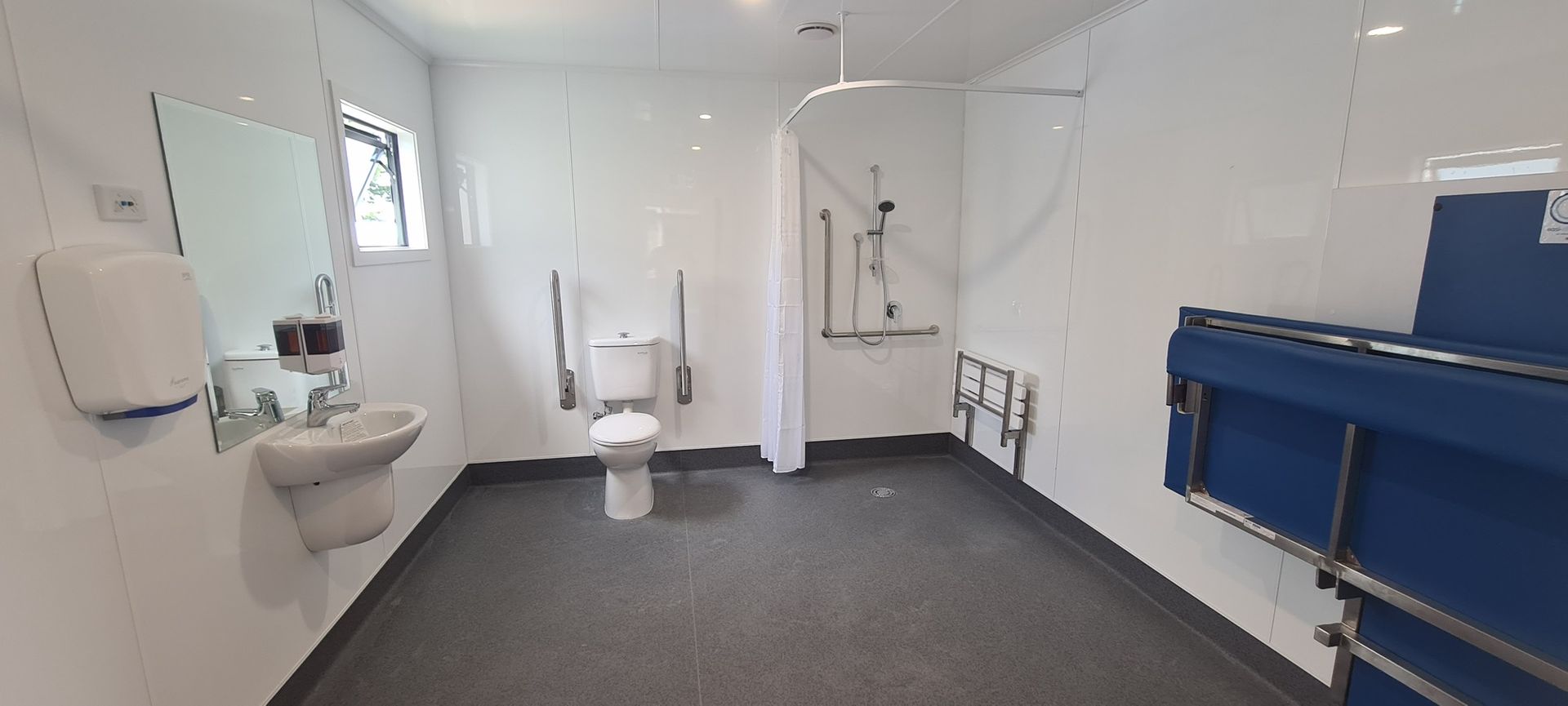 A bathroom with a toilet , sink and shower.