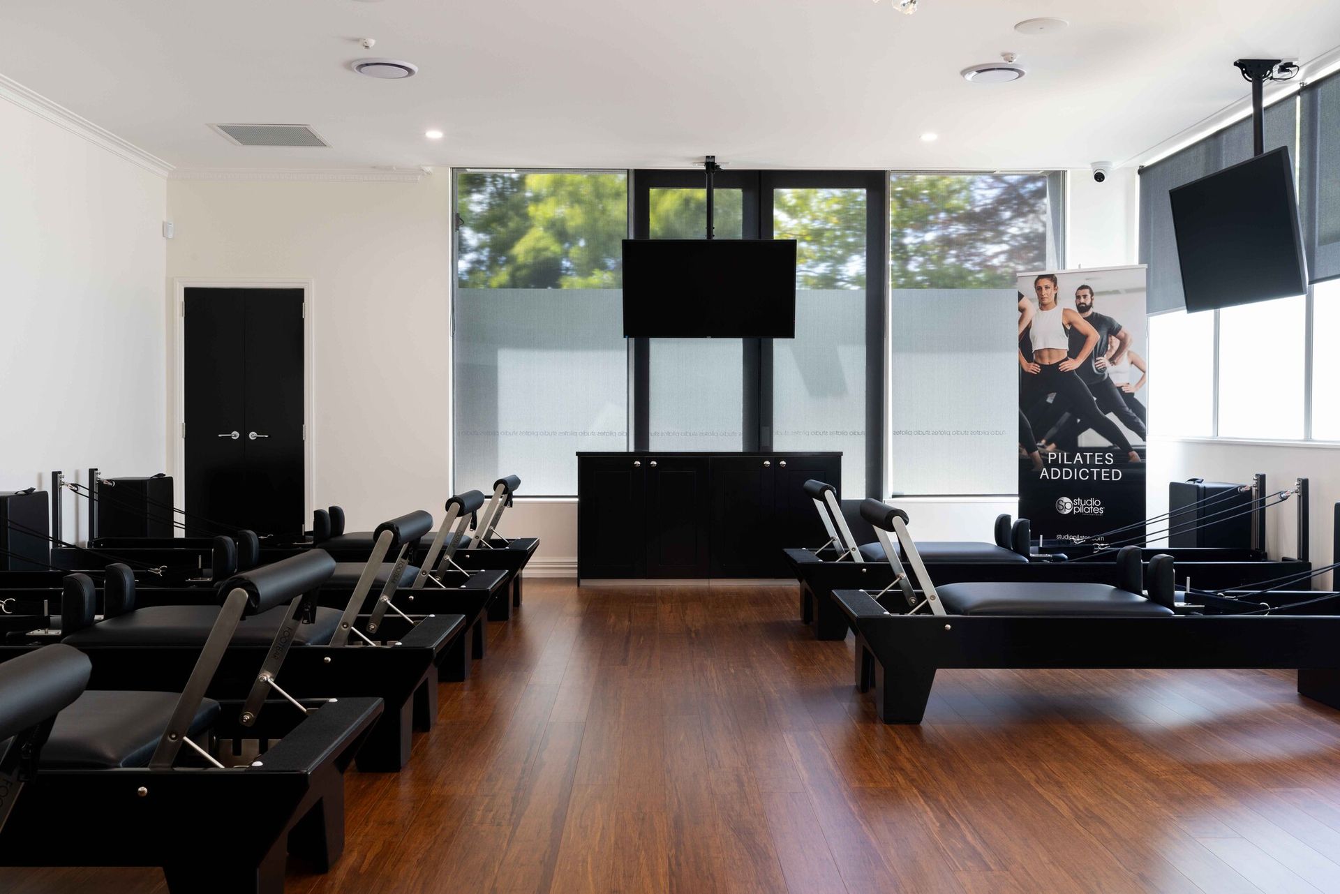 A gym with a lot of pilates machines and a tv on the wall.