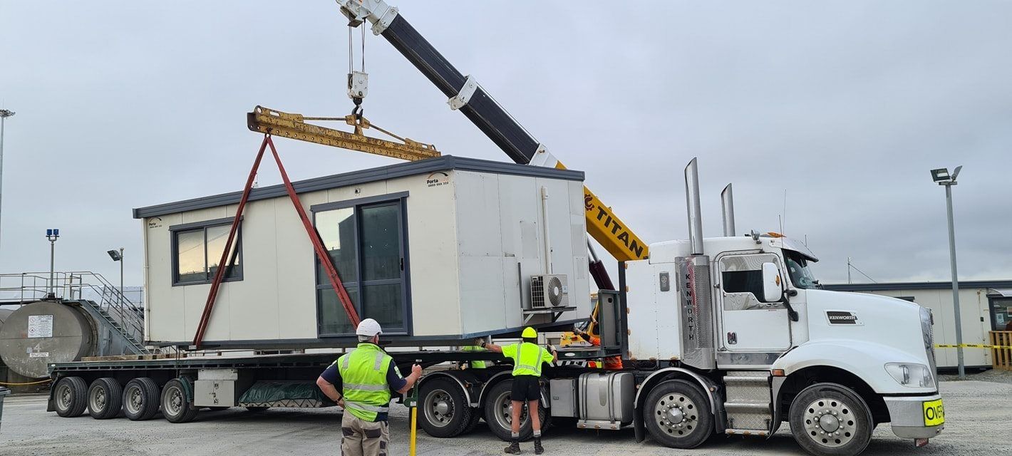 A truck is carrying a container with a crane attached to it.