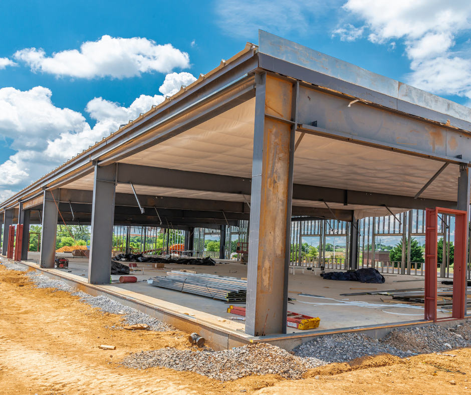 A large building is being built in the middle of a dirt field.