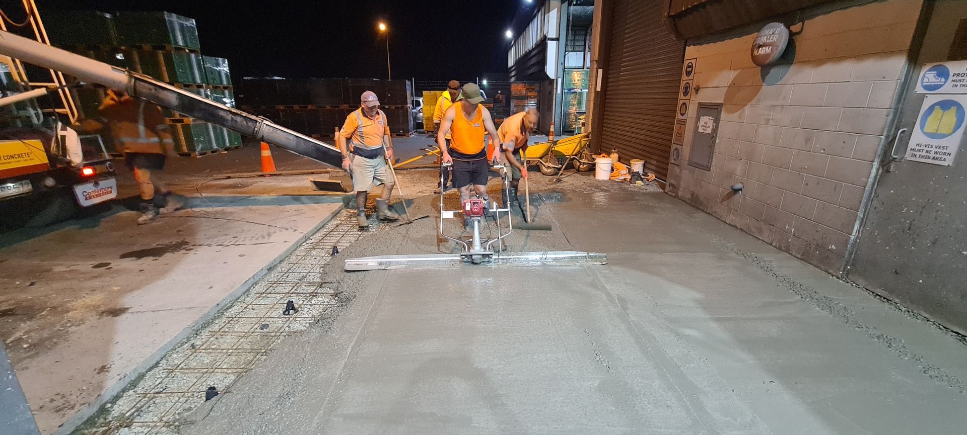 A group of construction workers are working on a road at night.