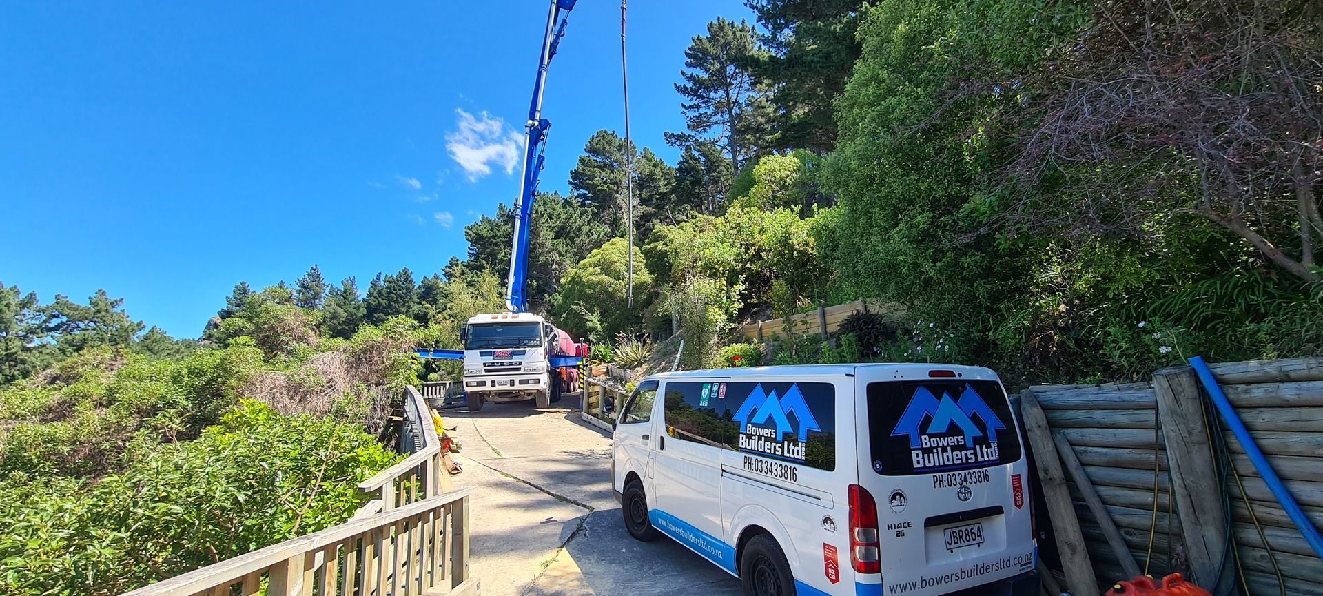 A white van is parked on the side of a road next to a crane.